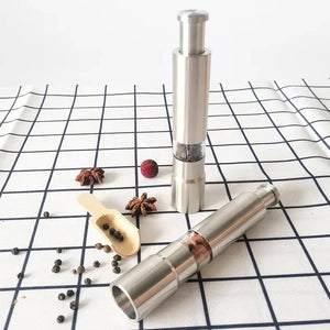 Two silver pepper mills with salt and pepper on a white background