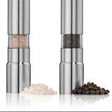 Two silver pepper mills with salt and pepper on a white background