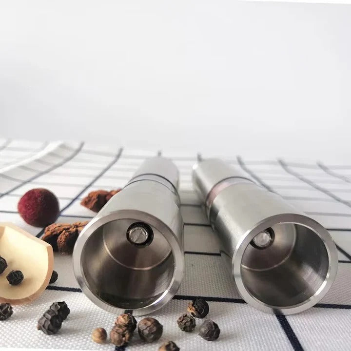 Two silver salt and pepper shakers on a white surface with black lines.